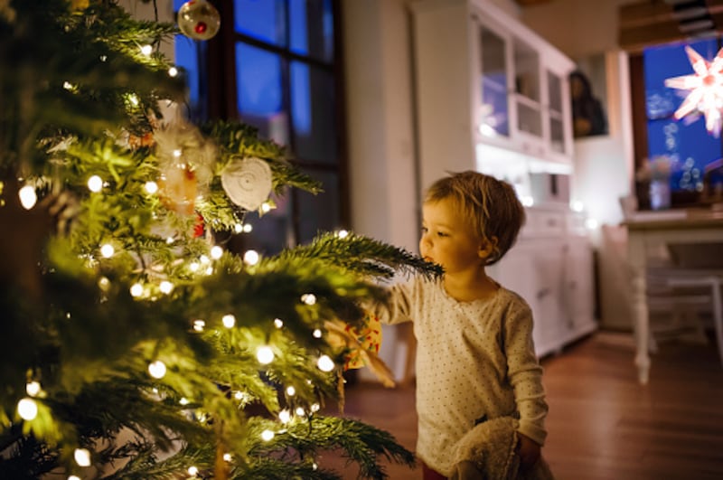 Un niño frente a un árbol de Navidad.